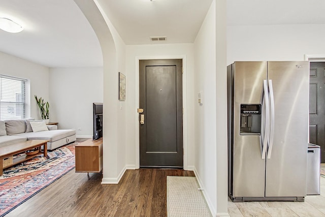 foyer entrance featuring light wood-type flooring, visible vents, arched walkways, and baseboards