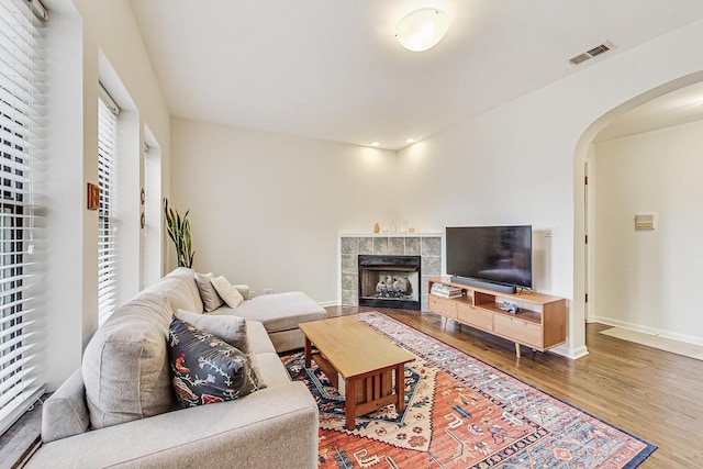 living area with baseboards, visible vents, arched walkways, wood finished floors, and a fireplace