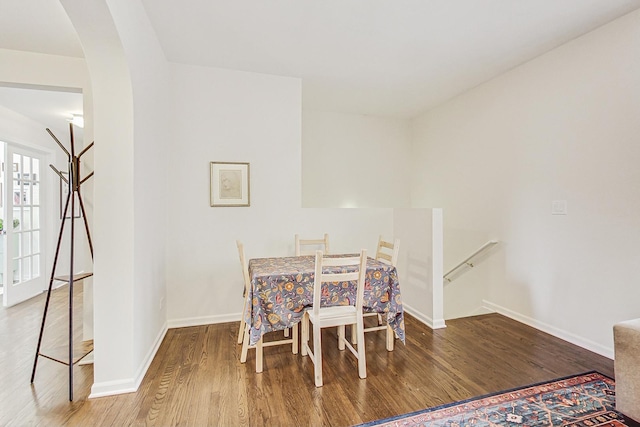 dining area featuring arched walkways, wood finished floors, and baseboards