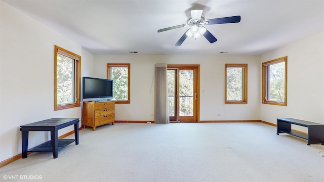 living room featuring light carpet, ceiling fan, visible vents, and baseboards