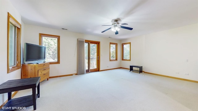 living area featuring visible vents, baseboards, ceiling fan, and light colored carpet