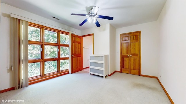 unfurnished bedroom with a ceiling fan, light colored carpet, visible vents, and baseboards