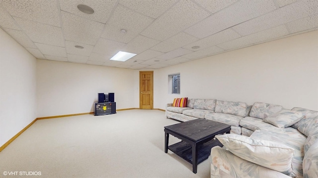 carpeted living area featuring a drop ceiling and baseboards