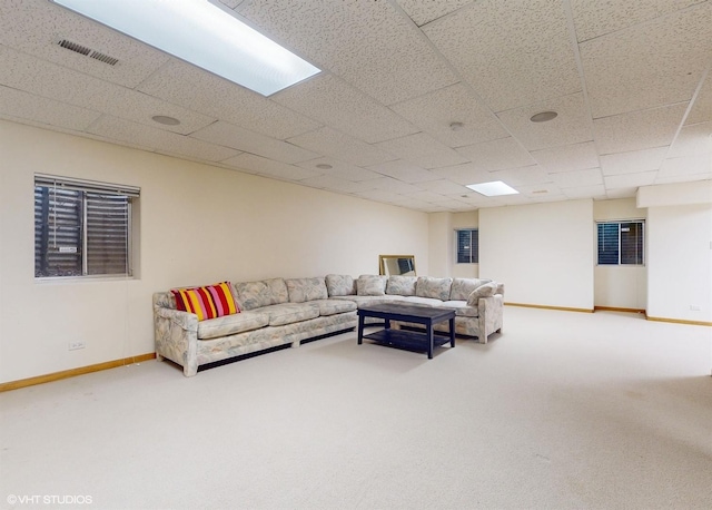 carpeted living area with a paneled ceiling, visible vents, and baseboards