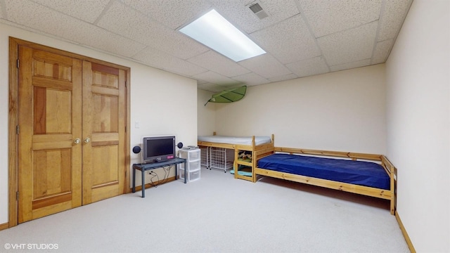 bedroom featuring carpet floors, baseboards, visible vents, and a drop ceiling