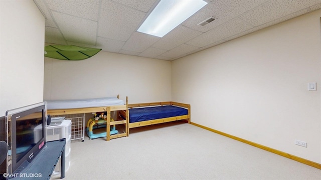 carpeted bedroom with a paneled ceiling, visible vents, and baseboards