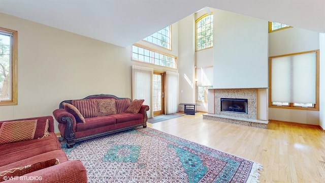 living area featuring baseboards, a premium fireplace, a high ceiling, and wood finished floors