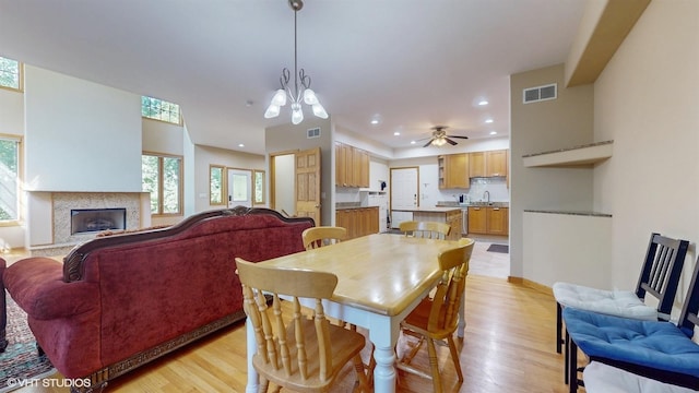 dining space featuring light wood-type flooring, a premium fireplace, visible vents, and recessed lighting