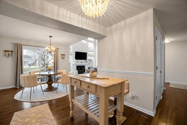 dining area with a notable chandelier, a fireplace, baseboards, and hardwood / wood-style flooring