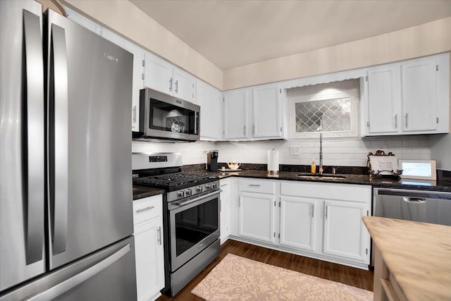 kitchen featuring tasteful backsplash, white cabinetry, stainless steel appliances, and a sink