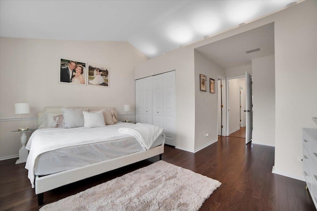 bedroom featuring visible vents, wood finished floors, a closet, baseboards, and vaulted ceiling