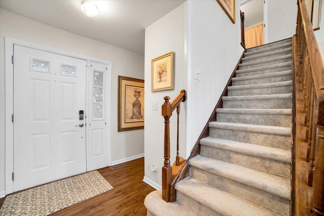 entryway featuring visible vents, stairway, baseboards, and wood finished floors