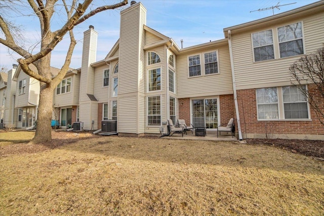 rear view of property with a patio area, central AC unit, a chimney, and brick siding