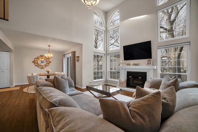 living area with an inviting chandelier, a fireplace, dark wood-style flooring, and baseboards