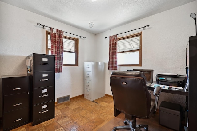 office area with visible vents, a textured ceiling, baseboards, and a textured wall