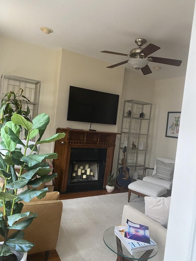 living area featuring ceiling fan and a fireplace with flush hearth