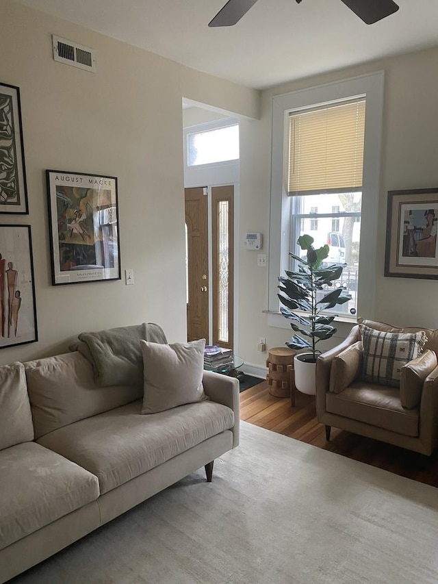 living area with ceiling fan, wood finished floors, and visible vents