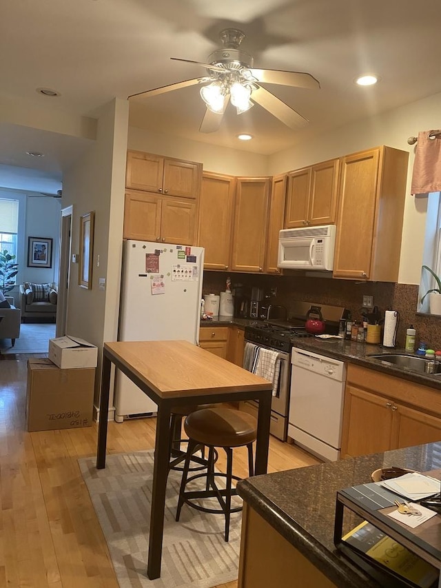 kitchen with light wood finished floors, decorative backsplash, a sink, ceiling fan, and white appliances