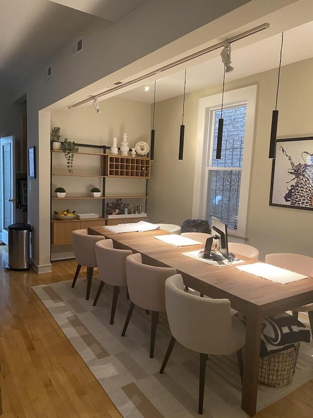 dining space with light wood-style floors, visible vents, and track lighting