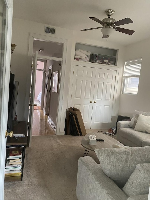 living room featuring visible vents, a ceiling fan, and carpet flooring