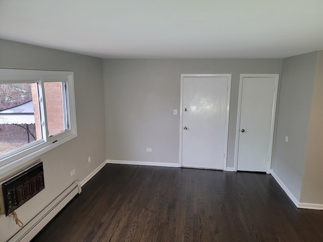 empty room with baseboards, dark wood-style flooring, and baseboard heating