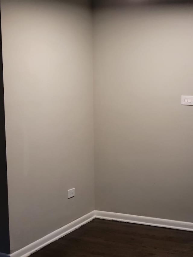 spare room featuring dark wood finished floors and baseboards