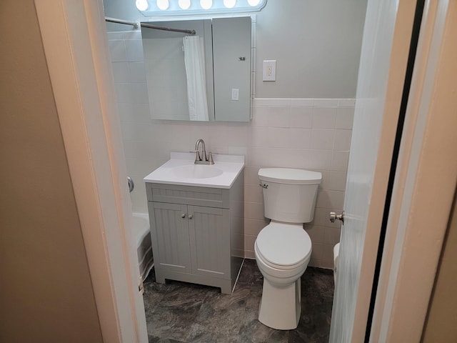 full bathroom with tile walls, toilet, vanity, and shower / tub combo