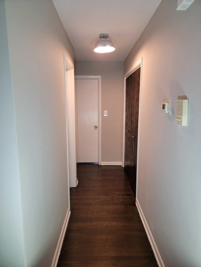 hallway featuring baseboards and dark wood-style floors