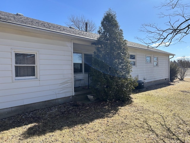 back of house featuring central air condition unit and roof with shingles