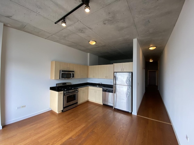 kitchen featuring a sink, stainless steel appliances, dark countertops, and dark wood finished floors