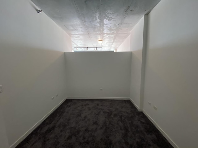 bonus room featuring dark carpet and baseboards