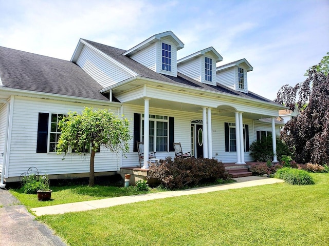 cape cod-style house with covered porch, a front lawn, and roof with shingles