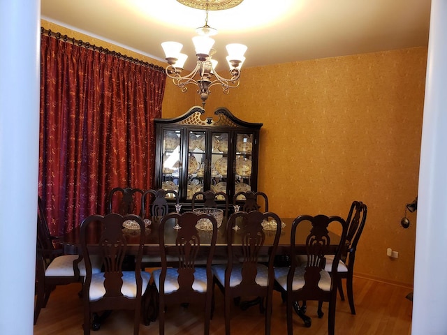 dining space featuring baseboards, an inviting chandelier, and wood finished floors