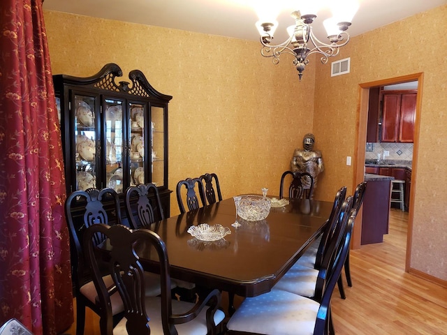 dining space featuring visible vents, an inviting chandelier, and wood finished floors