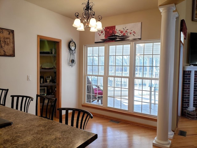 dining space featuring decorative columns, visible vents, and wood finished floors