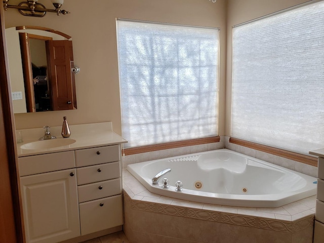 bathroom with a jetted tub, a healthy amount of sunlight, and vanity