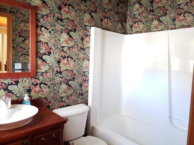 full bathroom with toilet, vanity, and wallpapered walls