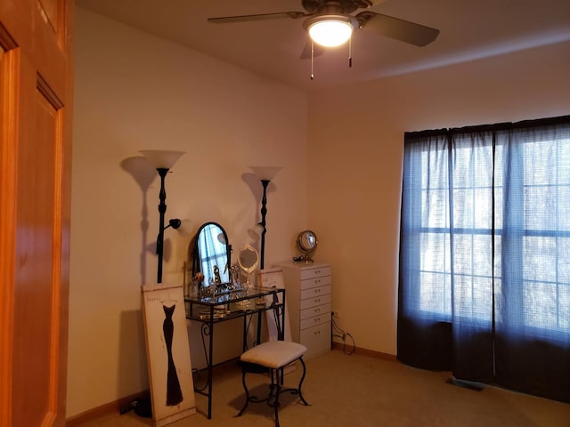 interior space featuring baseboards, light carpet, and ceiling fan