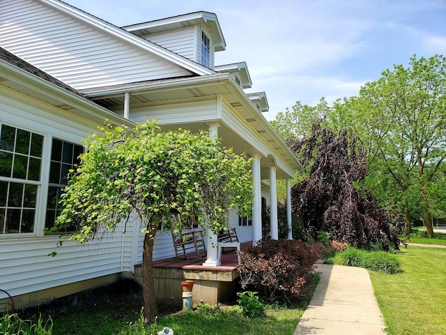 view of side of home featuring a lawn and a porch