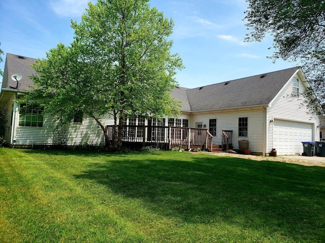 back of property with driveway, roof with shingles, a garage, a deck, and a lawn