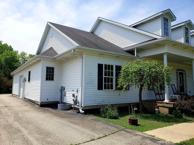 view of property exterior with a porch, driveway, and a shingled roof