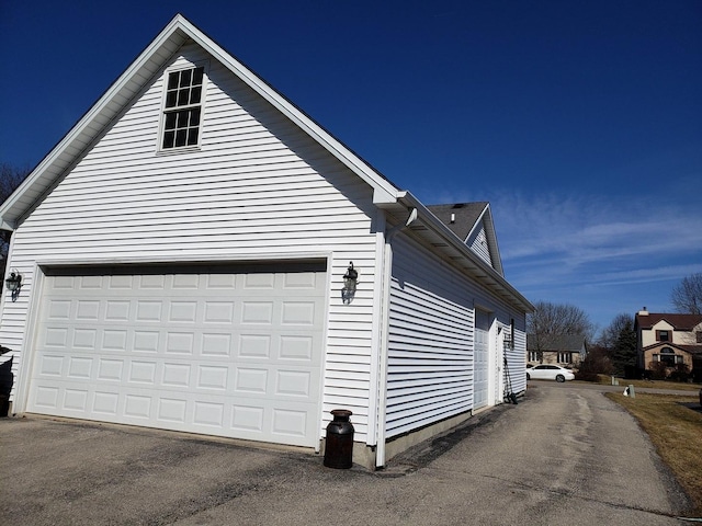 view of side of property featuring aphalt driveway and a garage