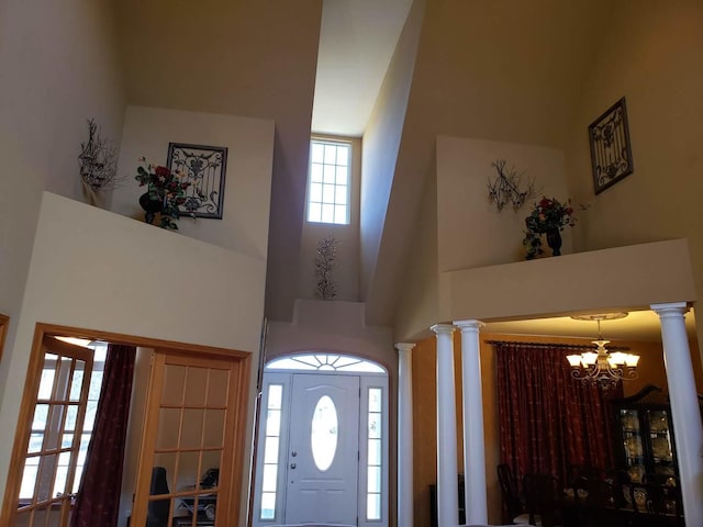 foyer with a high ceiling, an inviting chandelier, and ornate columns