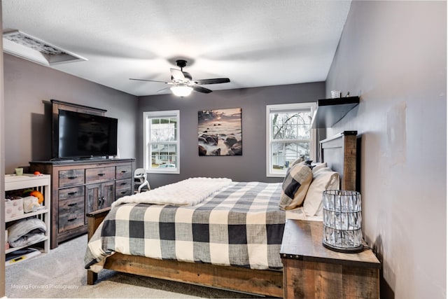 bedroom with a textured ceiling, carpet, and a ceiling fan