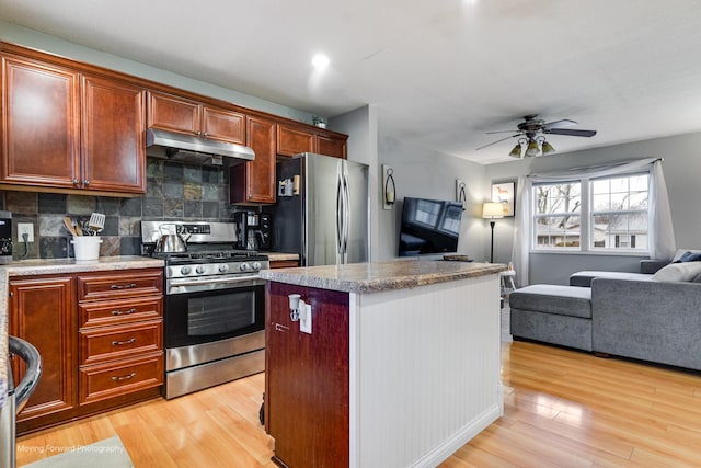 kitchen with stainless steel appliances, tasteful backsplash, open floor plan, light wood-type flooring, and under cabinet range hood