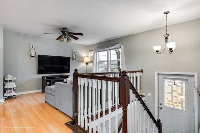 interior space with ceiling fan with notable chandelier, wood finished floors, and baseboards