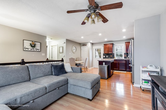 living area featuring ceiling fan, light wood finished floors, baseboards, and recessed lighting