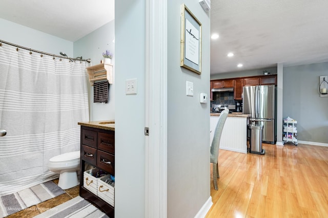 full bath featuring toilet, recessed lighting, wood finished floors, vanity, and decorative backsplash