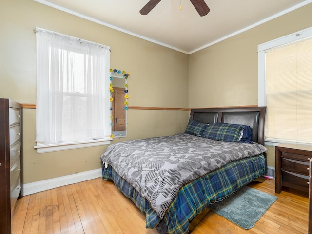 bedroom with ornamental molding, a ceiling fan, baseboards, and hardwood / wood-style floors