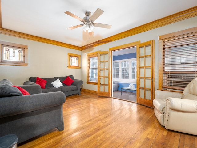 living area with crown molding, ceiling fan, baseboards, french doors, and hardwood / wood-style flooring
